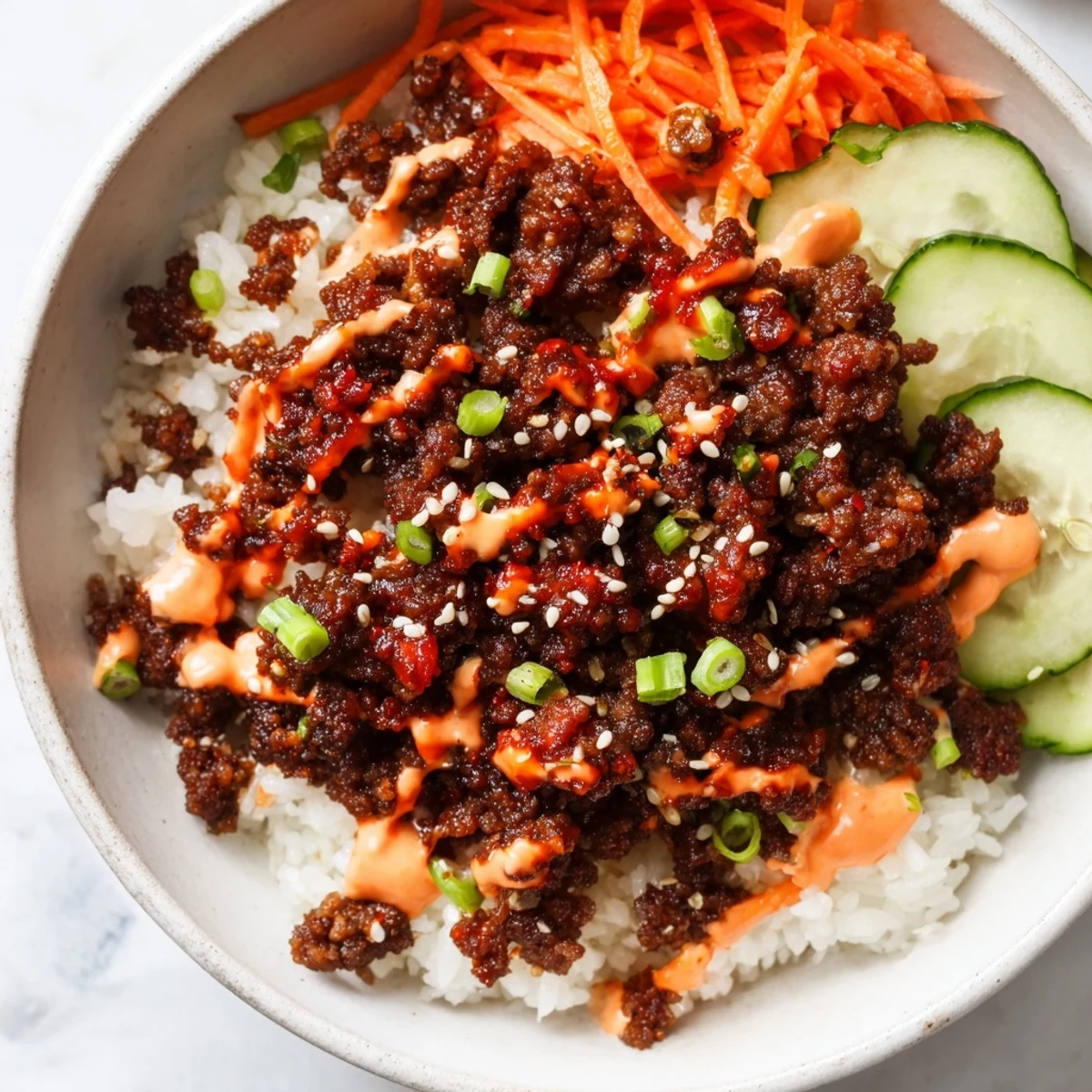 Vibrant rice bowl topped with caramelized Korean beef, shredded vegetables, and homemade spicy mayo sauce