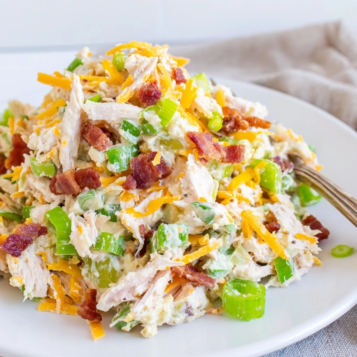 Scoop of spicy low carb chicken salad topped with cheddar cheese and crispy bacon crumbles