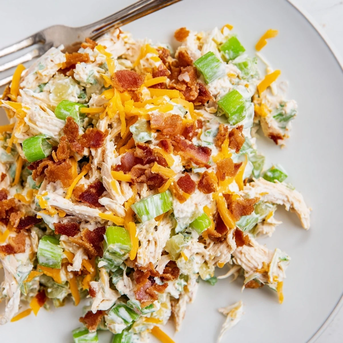 Keto chicken salad featuring jalapeno popper flavors served in bowl with fresh celery sticks