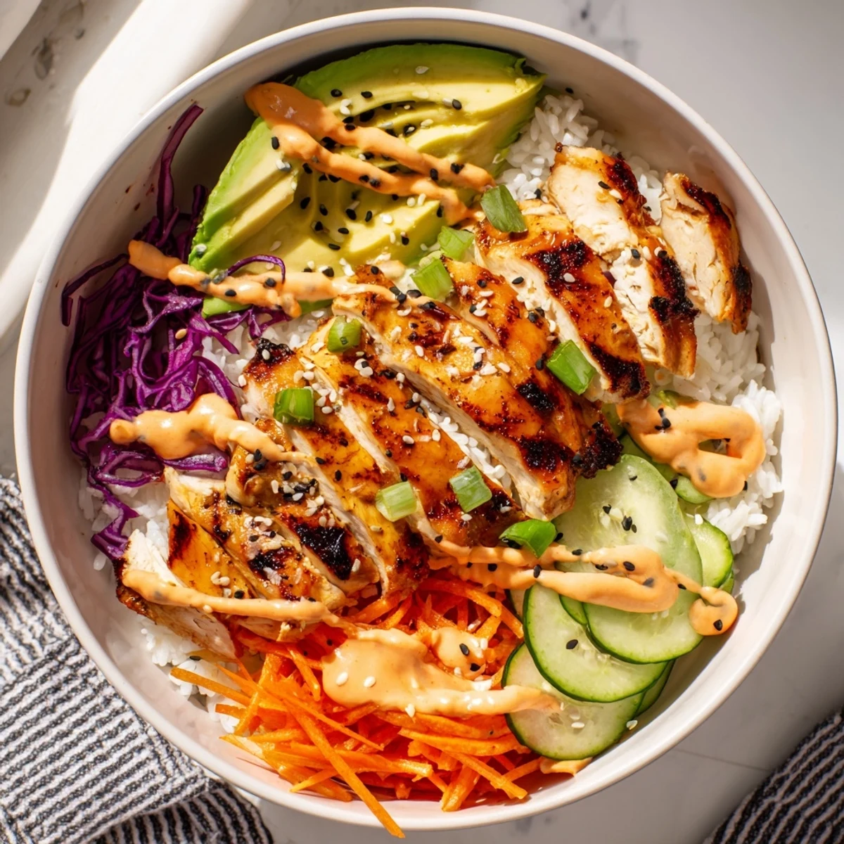Vibrant Korean BBQ chicken bowls arranged with marinated sliced chicken, shredded purple cabbage, cucumber, carrots, and creamy spicy mayo topping