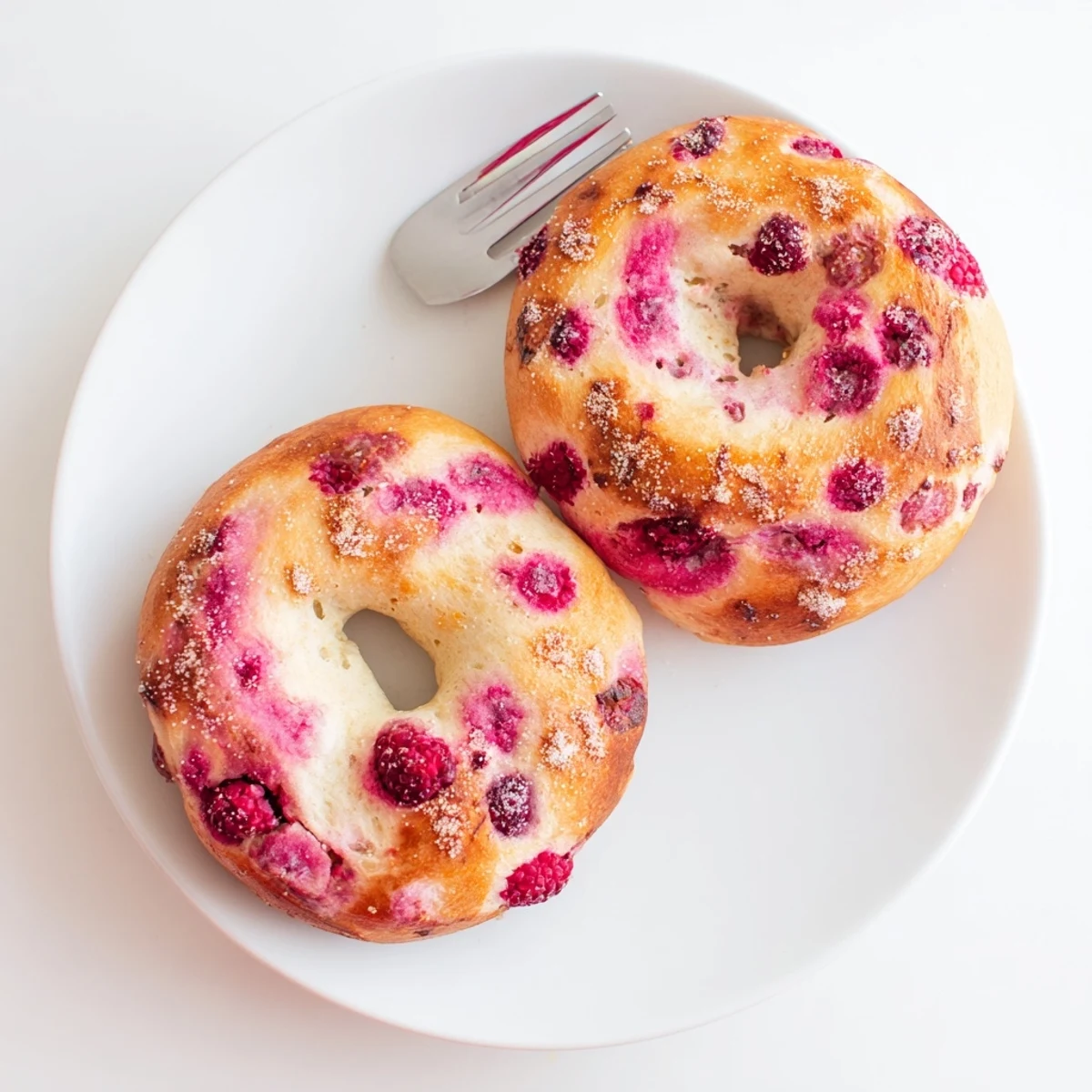 Homemade raspberry sourdough bagels arranged on a wire rack, fresh from the oven