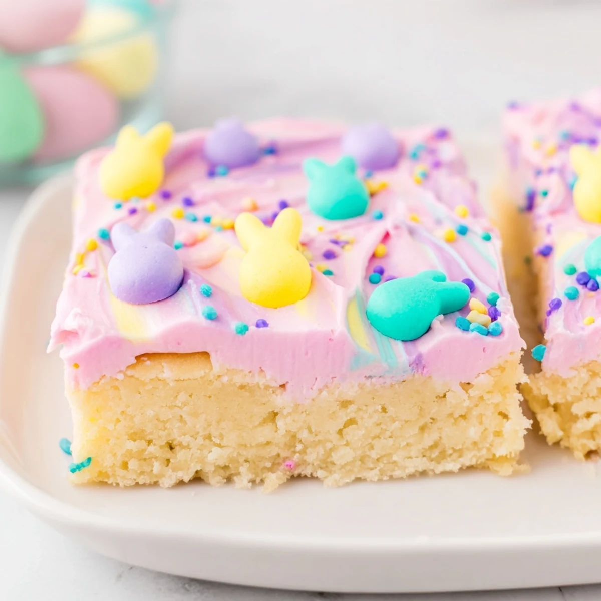 Thick-cut Easter sugar cookie bars topped with smooth pink buttercream and festive candy sprinkles
