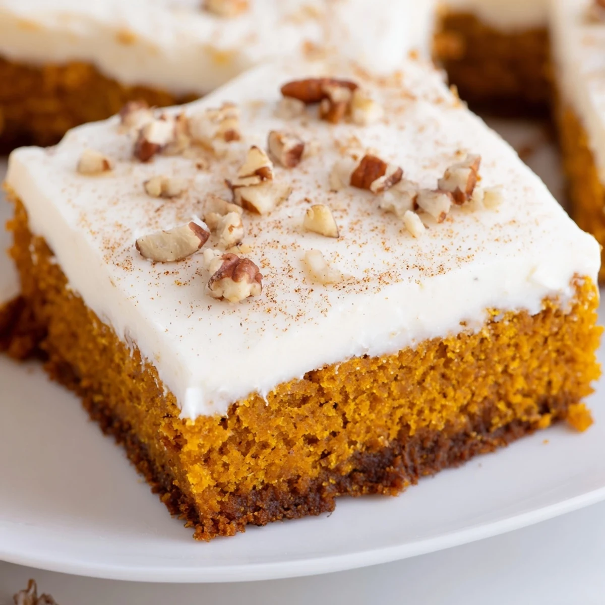 Warm spiced pumpkin bars with thick cream cheese frosting swirled atop each moist piece