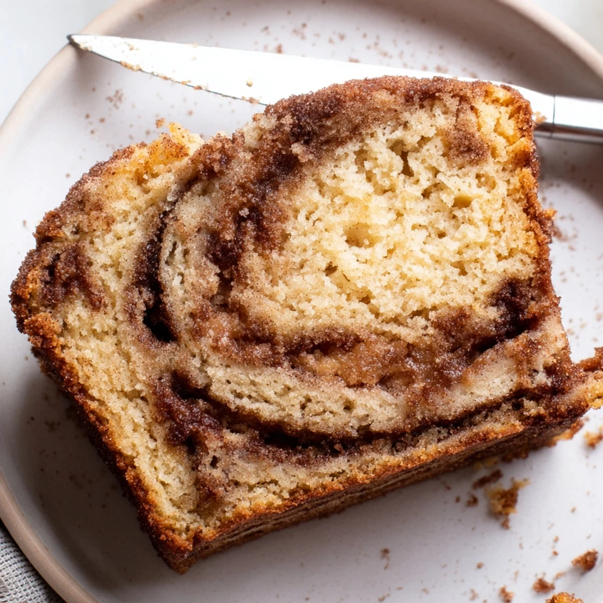 A thick slice of snickerdoodle banana bread served with melted butter on a ceramic plate