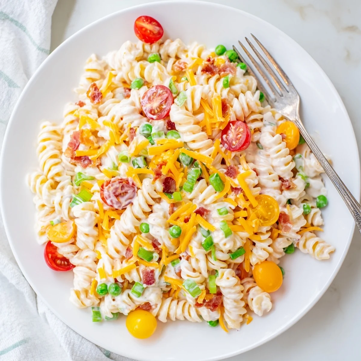Chilled crack pasta salad in a serving dish with diced bell peppers and peas