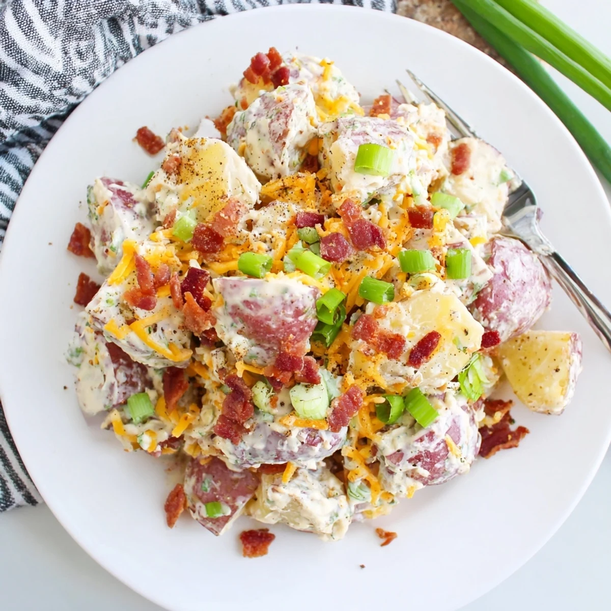 Beef Bacon Loaded Potato Salad on a platter, creamy, crispy bacon, parsley.