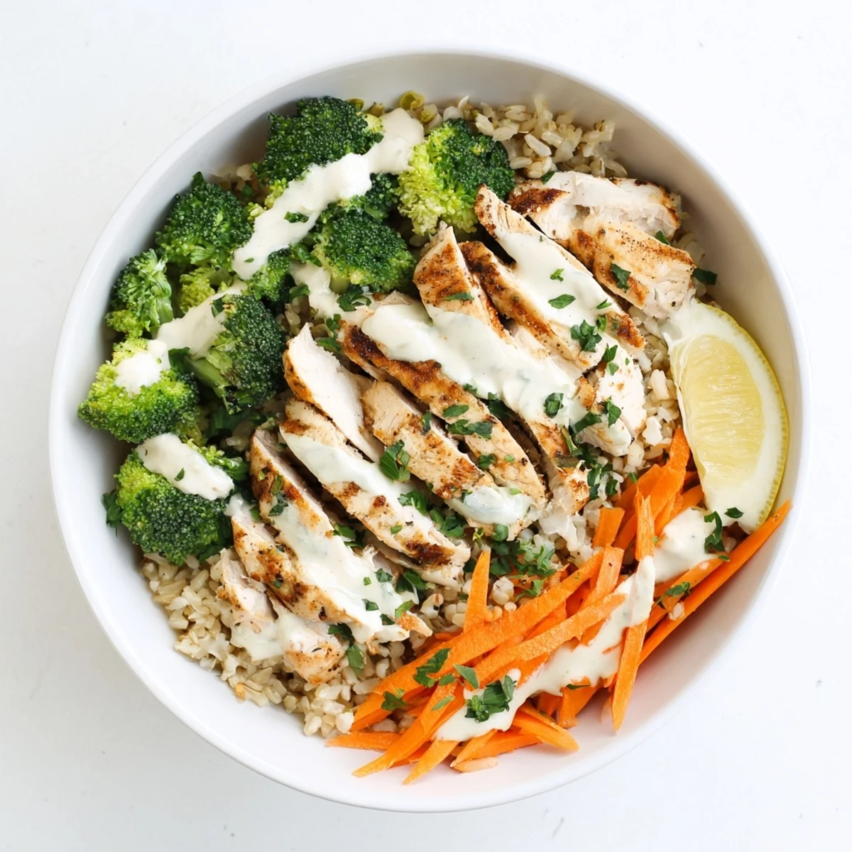 Golden brown grilled chicken slices arranged over steamed broccoli florets drizzled with creamy white garlic sauce