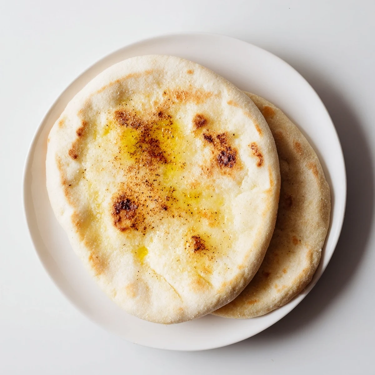 Freshly cooked Turkish Bazlama flatbread rounds stacked on kitchen towel warm and steaming