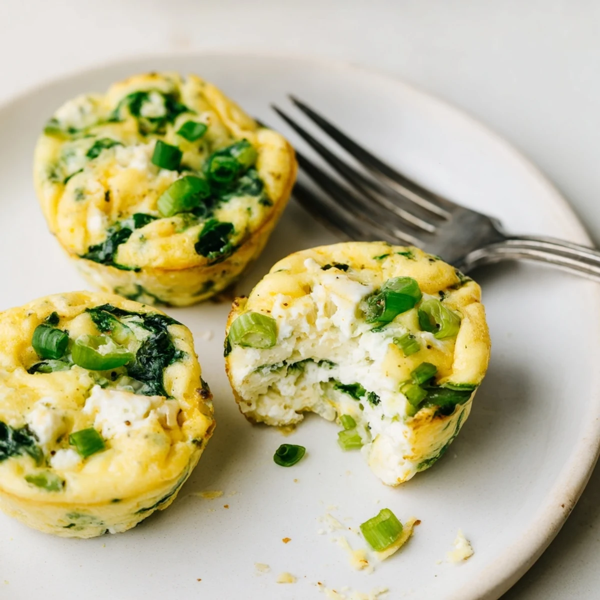 Savory Spinach Feta Egg Bites arranged on plate with tomato salsa, herb aroma.