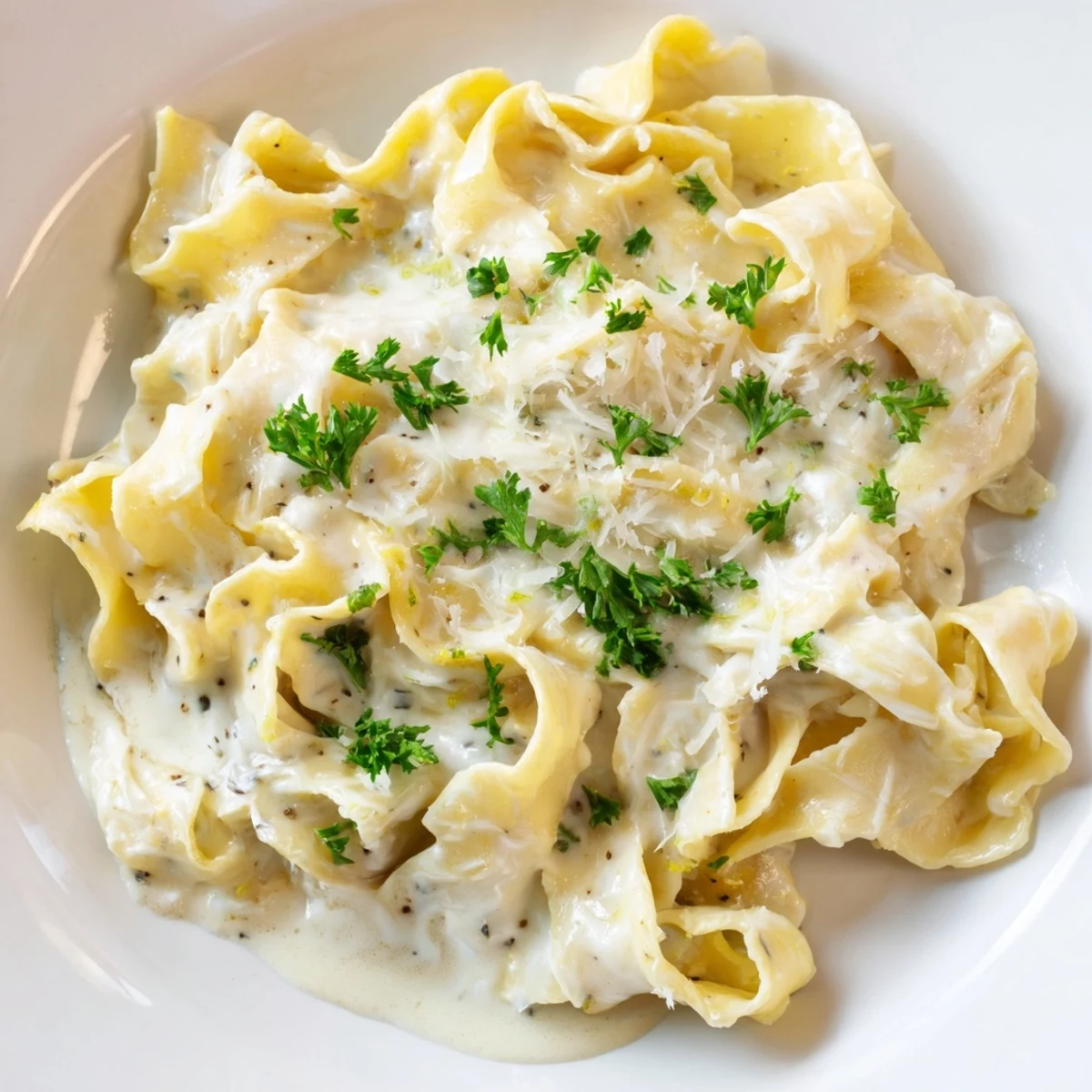 Steaming bowl of tender egg noodles coated in velvety smooth cheese sauce topped with grated Parmesan and herbs