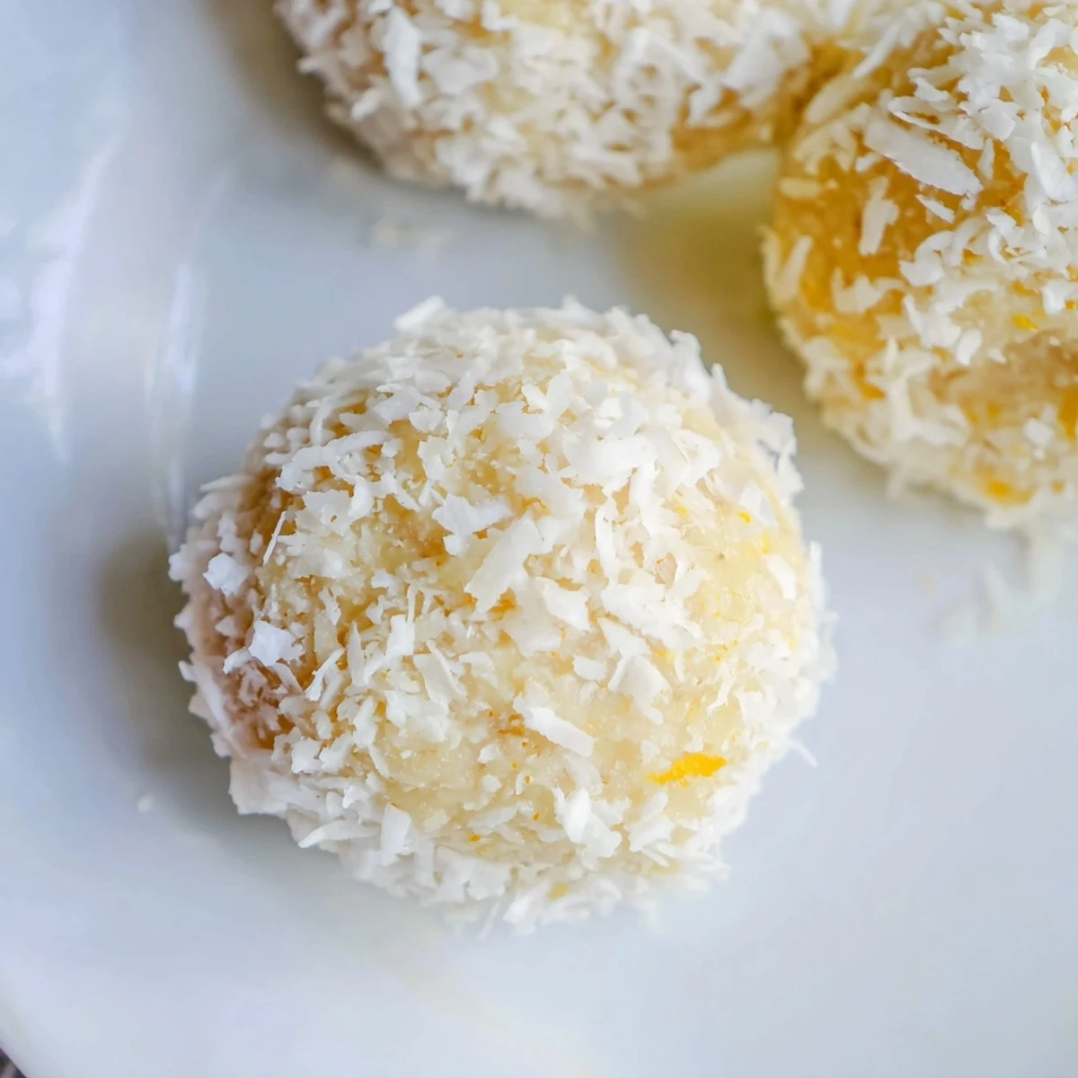 Bite-sized orange and lemon coconut balls chilled on a rustic wooden board