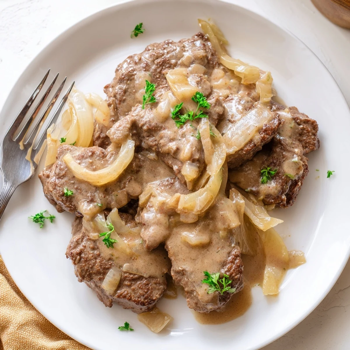 Country style cube steak dinner with golden onions and savory brown gravy plated for comfort food meal
