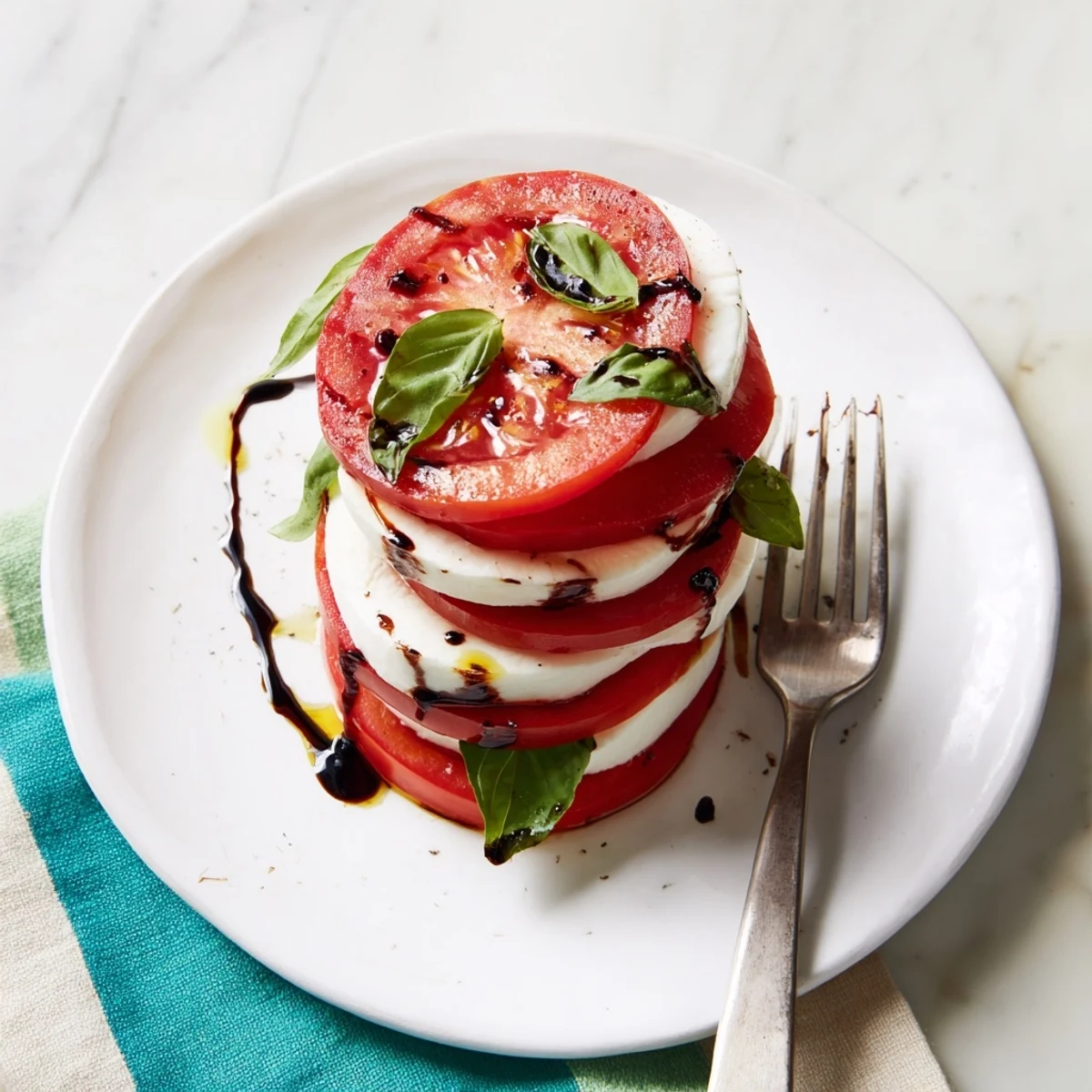 Caprese Salad with ripe tomato and mozzarella slices, basil and olive oil.