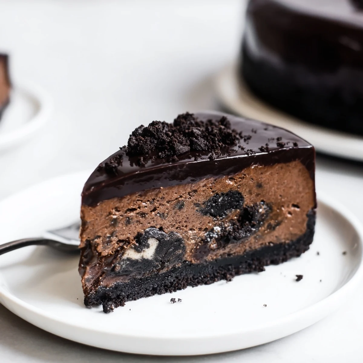 Creamy Oreo chocolate cheesecake with glossy ganache topping on a dark cookie crust