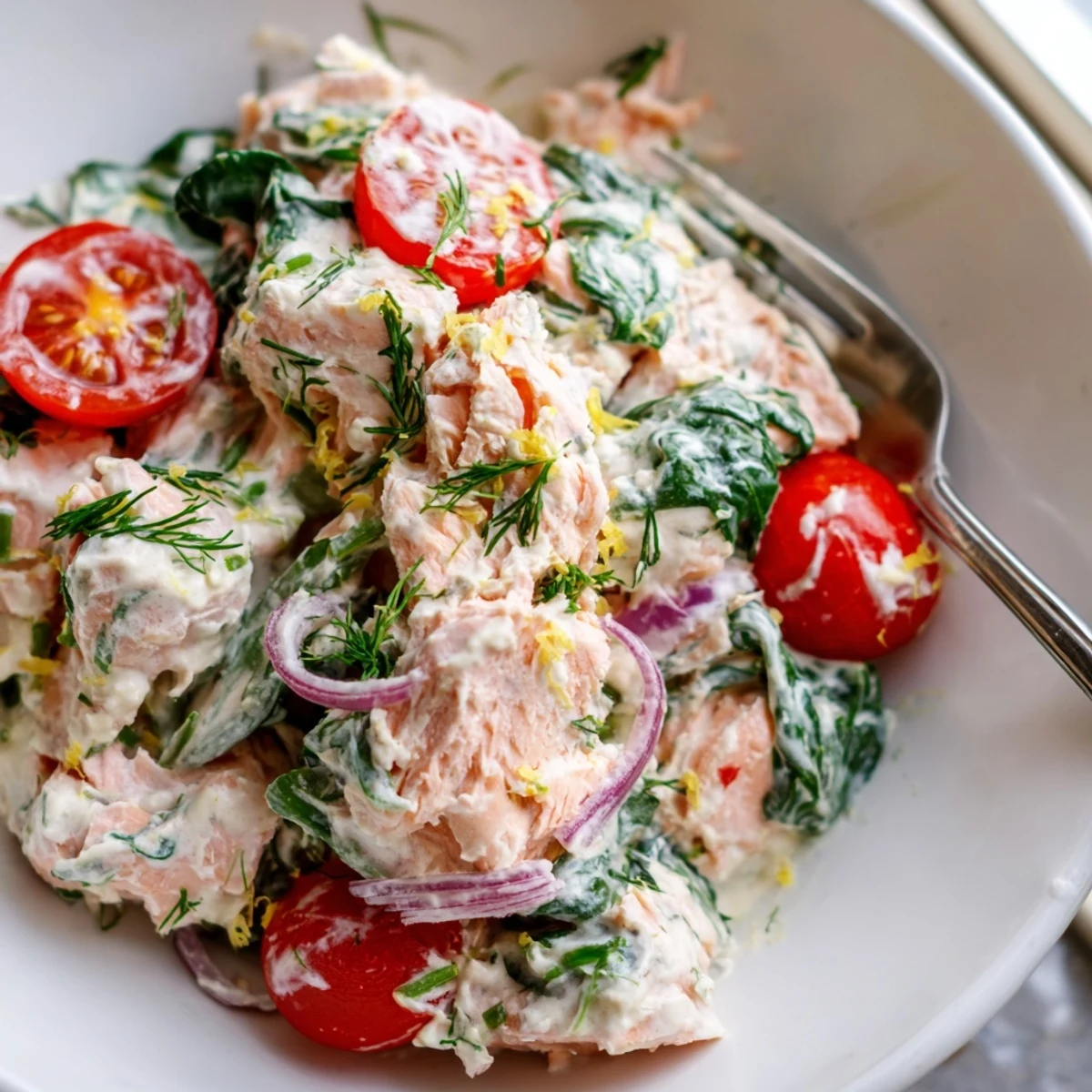 Creamy leftover salmon recipe plated with wilted spinach, cherry tomatoes, and fresh dill
